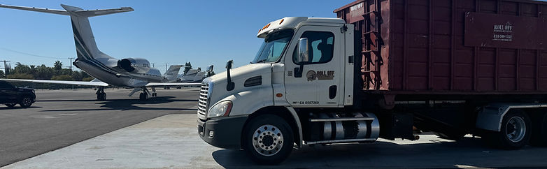 Roll Off Truck next to private jet at a local Commercial airport job site.